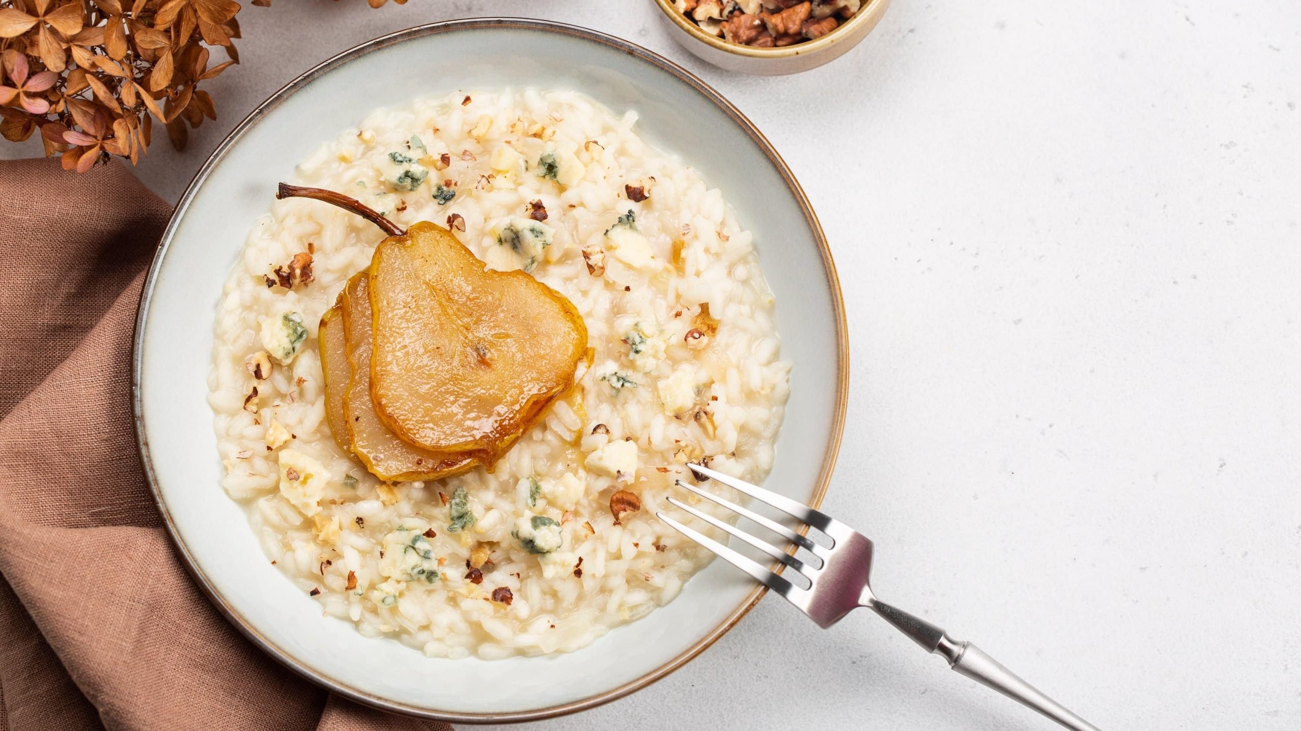 Risotto mit Gorgonzola und karamellisierter Birne auf Teller angerichtet.