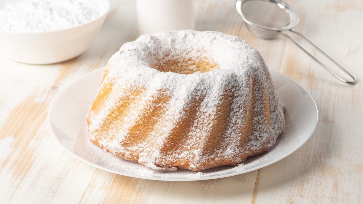 Saftiger Sandkuchen auf weißem Teller mit Puderzucker garniert.