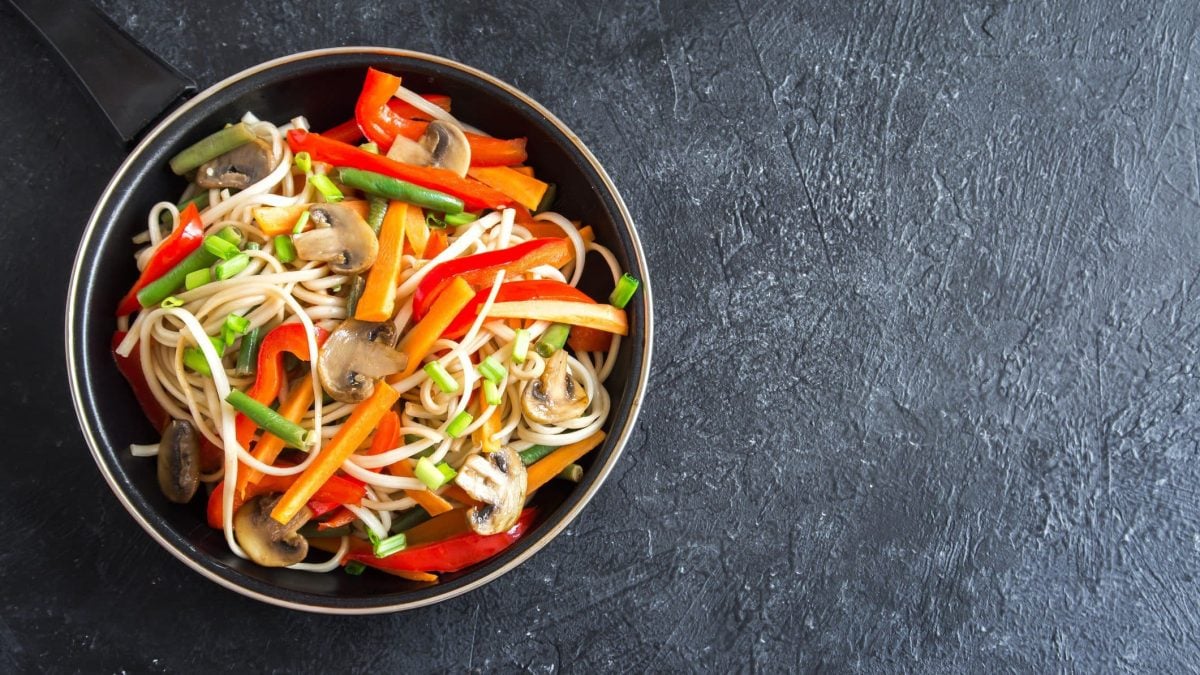 Eine Pfanne mit asiatischem Nudelsalat mit Möhren, Paprika, Bohnen und Pilzen