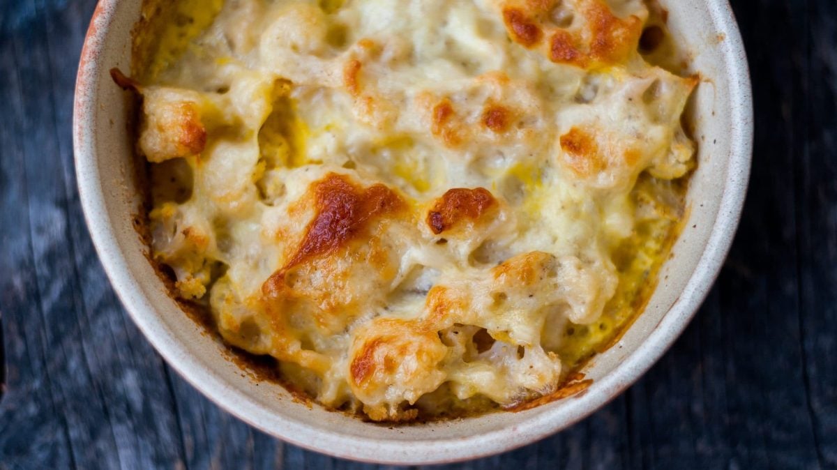 Der Blumenkohl-Auflauf mit Mozzarella goldbraun gebacken in einer runden Auflaufform.