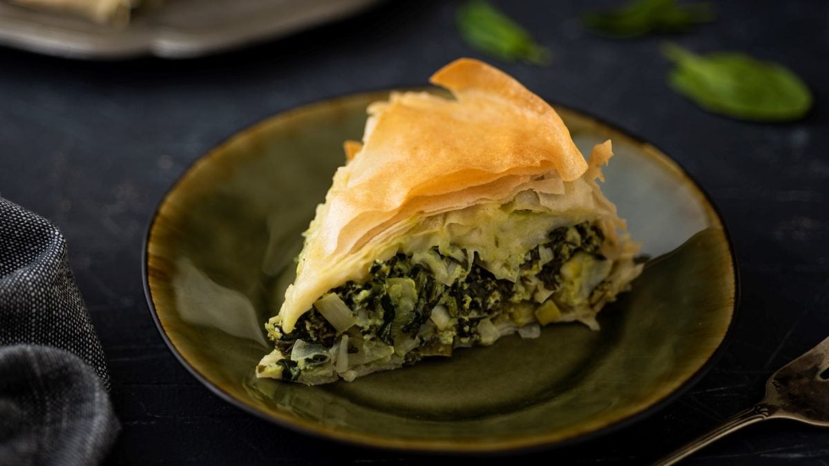Ein Teller, auf dem ein Stück Börek mit Mangold und Schafskäse liegt.