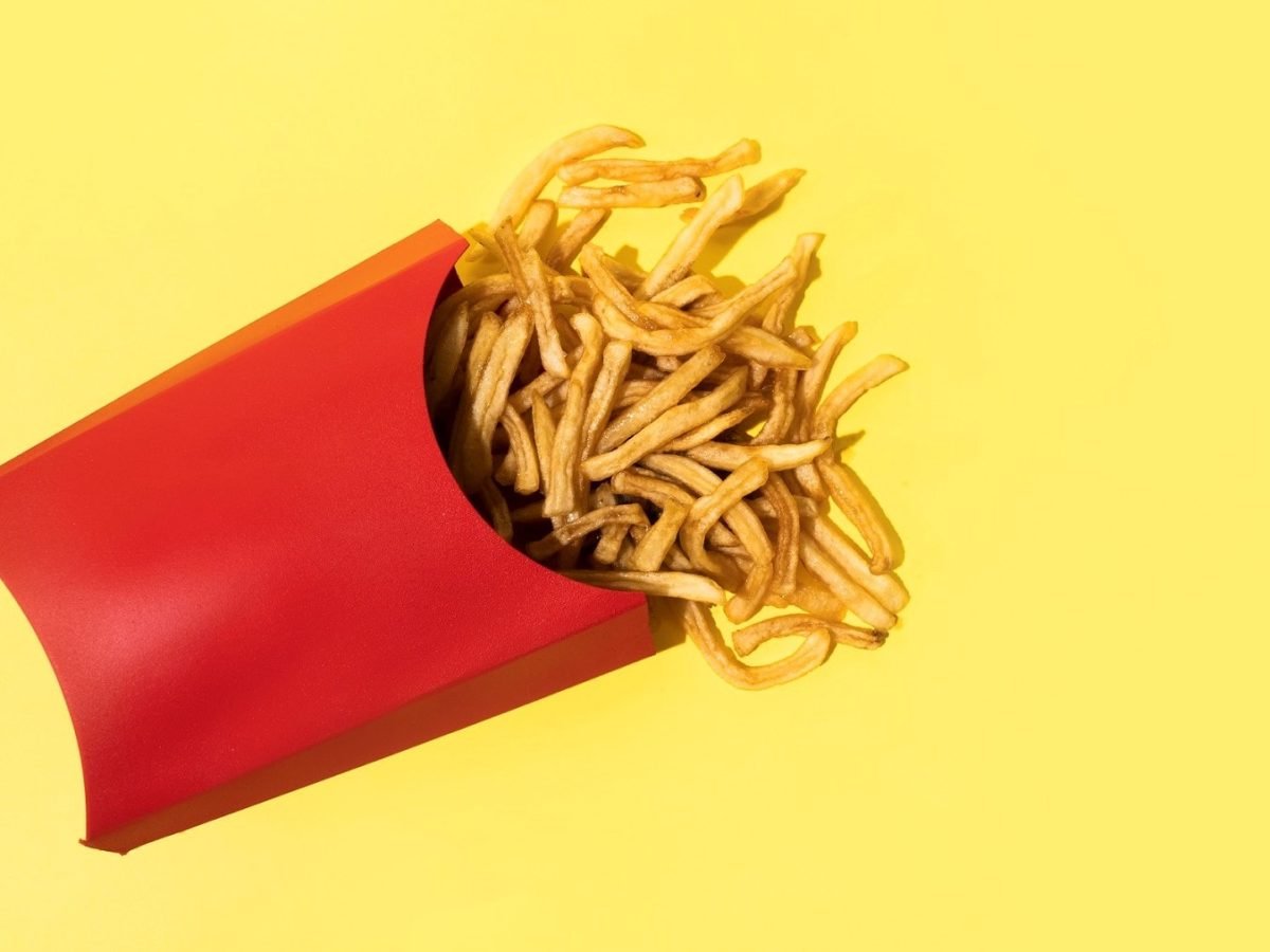 Eine rote Tüte mit Pommes auf einem weißen Untergrund