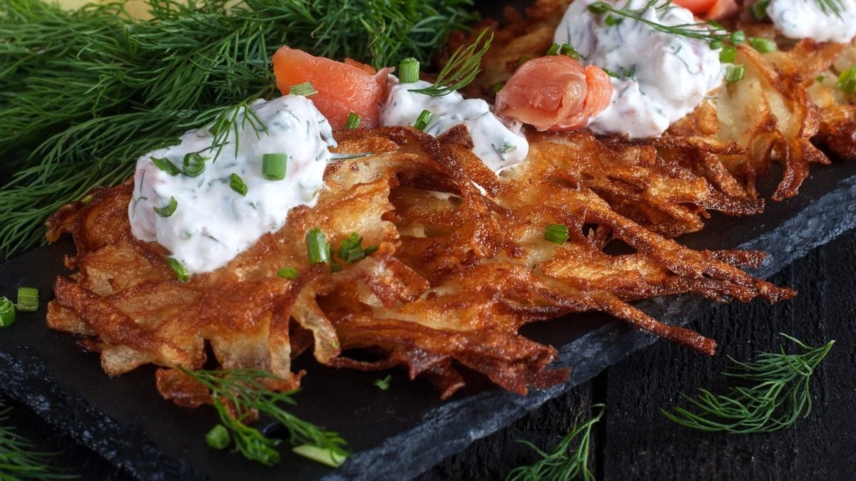 Kartoffelpuffer mit Lachs und Estragonquark, umringt von frischen Dillzweigen.