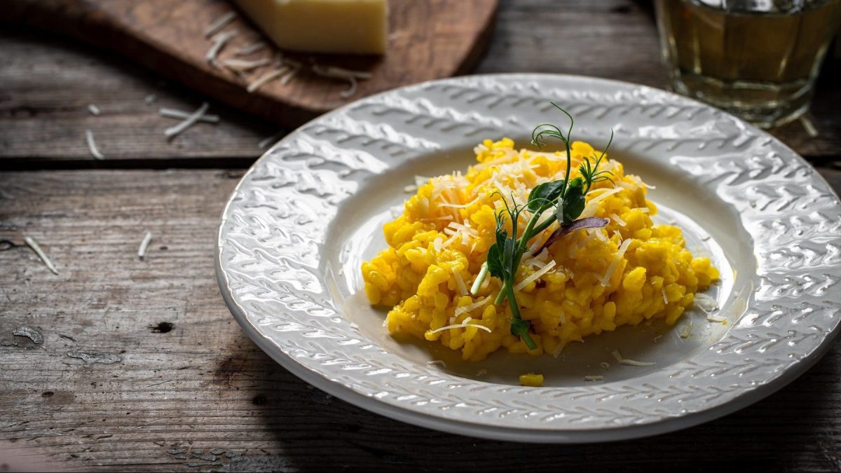 Auf einem weißen Teller ist Reis zu sehen. es handelt sich um ein Risotto alla milanese