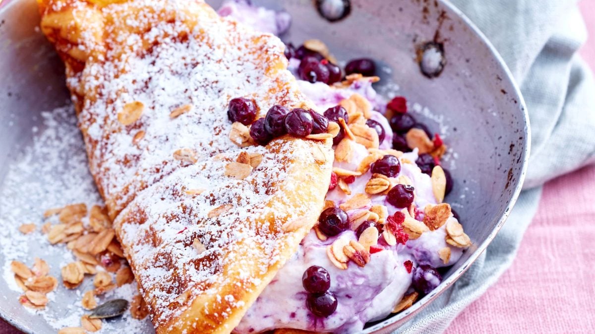Blick von oben: Auf einem Teller liegt eine zusammen geklappte Waffel mit Heidelbeeren.