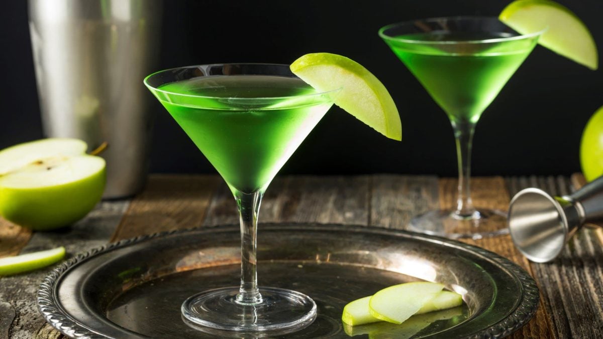 Zwei Gläser Appletini neben Cocktail-Zubehör