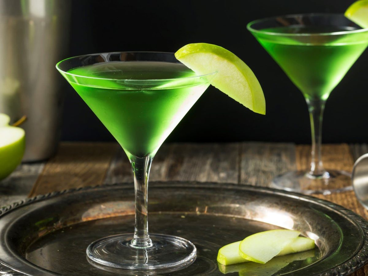 Zwei Gläser Appletini neben Cocktail-Zubehör