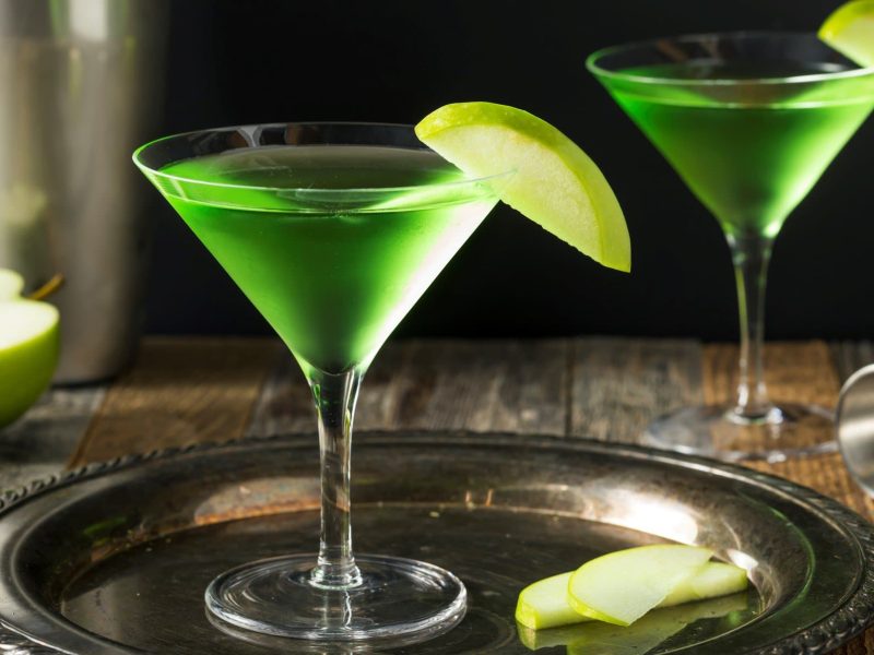 Zwei Gläser Appletini neben Cocktail-Zubehör