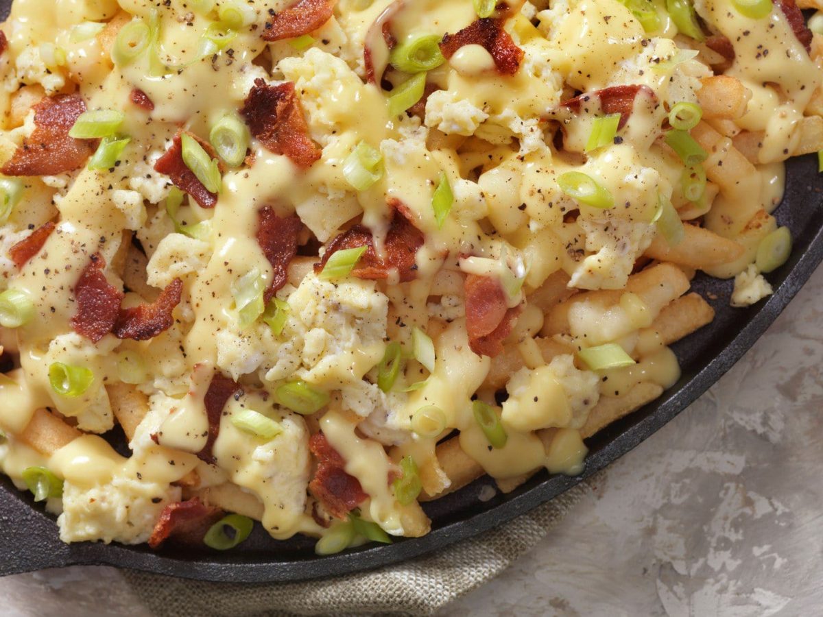 Poutine mit Frühstücks-Flair – Pommes belegt mit Sauce hollandaise, Käse, Bacon und Rührei