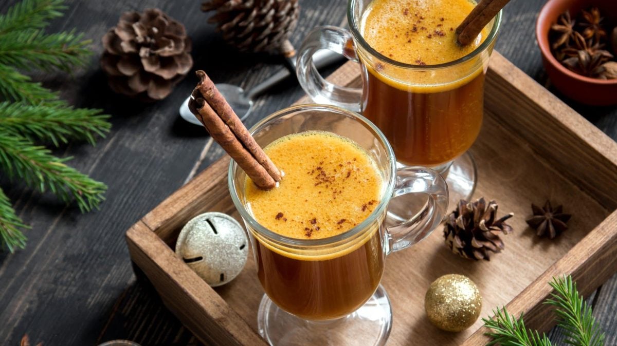 Der Hot Buttered Rum abgefüllt in zwei Trinkgläser. Rundherum weihnachtliche Deko.