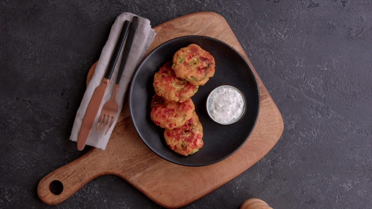Lachs-Kroketten mit Dip auf schwarzem Teller.