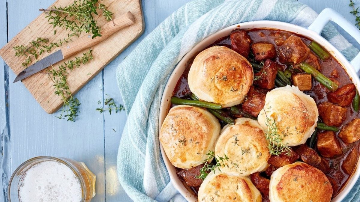 Bier-Gulasch und Brötchen gemeinsam angerichtet in einem Topf. Dazu Thymian als Deko und ein kühles Bier.