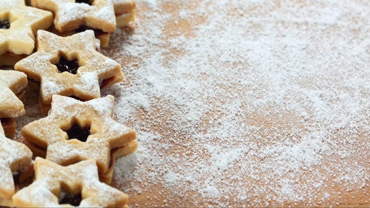 Auf einer bemehlten Arbeitsfläche sind mehrere glutenfreie Linzer Sterne.