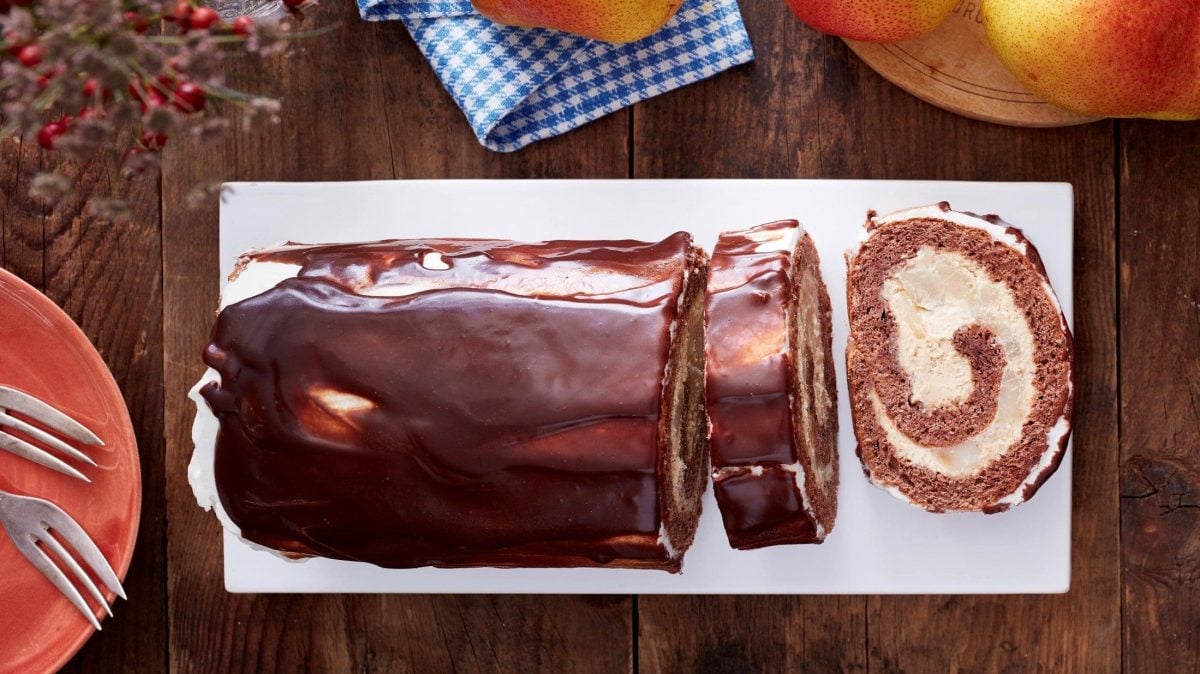 Unsere Schoko-Birnen-Rolle liegt angeschnitten auf einer Kuchenplatte.