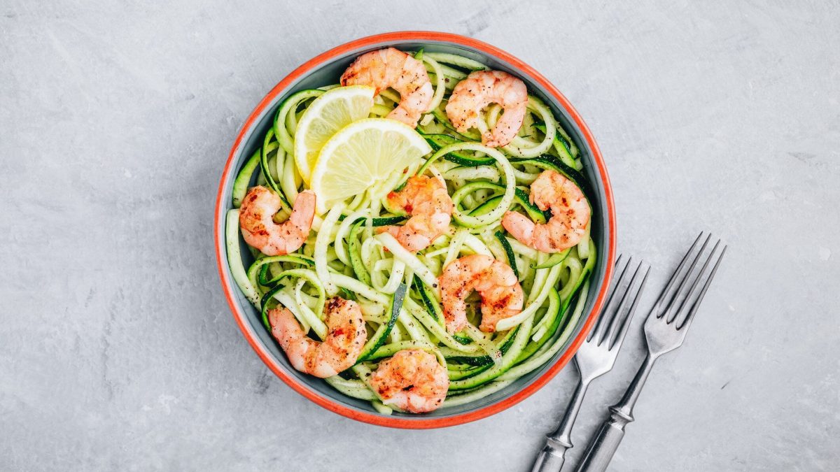Eine Schale in der Draufsicht auf Marmoruntergrund, darin Zoodles mit Garnelen.