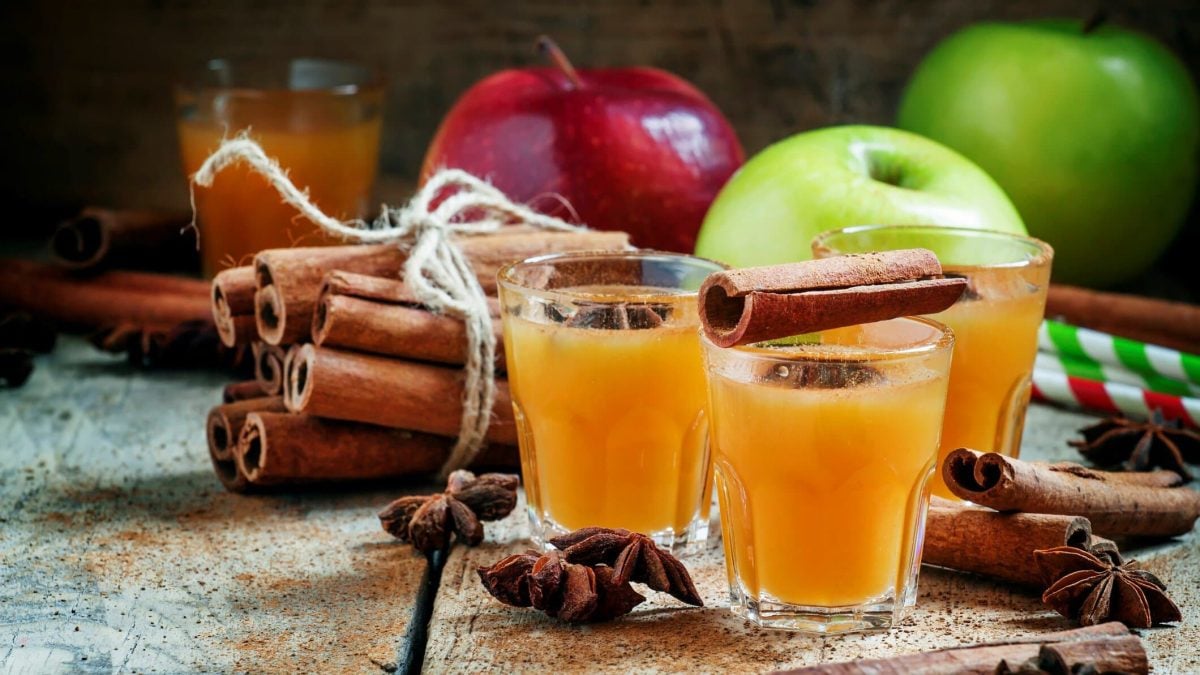 Drei Gläser mit Apfel-Glüh-Gin umgeben von den Zutaten