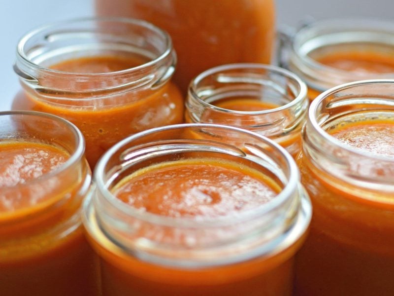 Orange-hellrote Habanero Hot Sauce in verschieden großen offen Einmachgläsern aus der Frontalsicht.