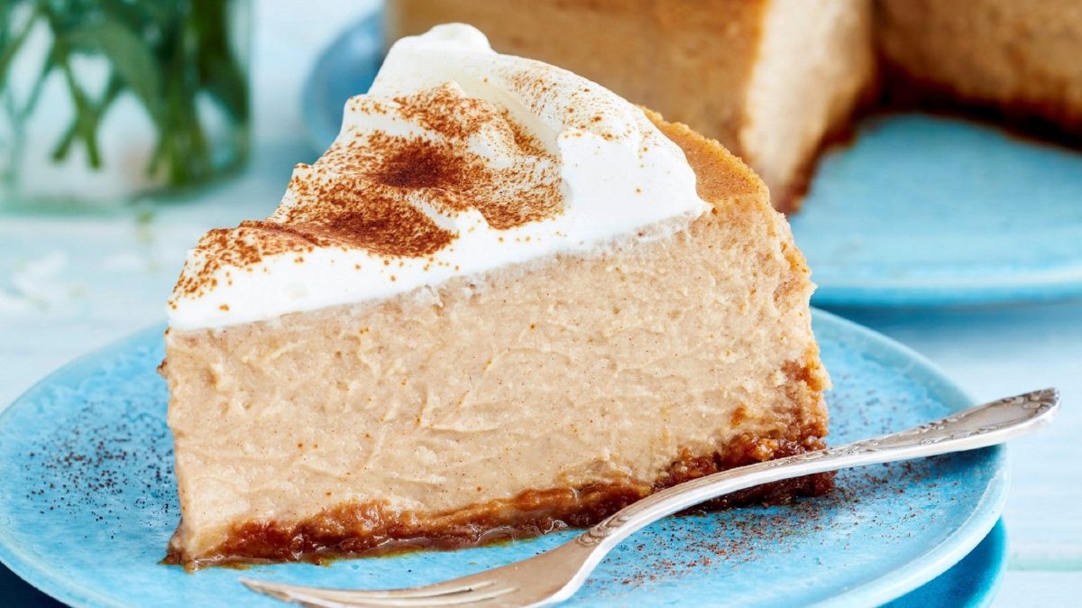 Auf einem blauen Teller liegt ein Stück Kaffee-Käsekuchen. Er ist mit einer Creme bestrichen und mit Espressopulver bestreut.