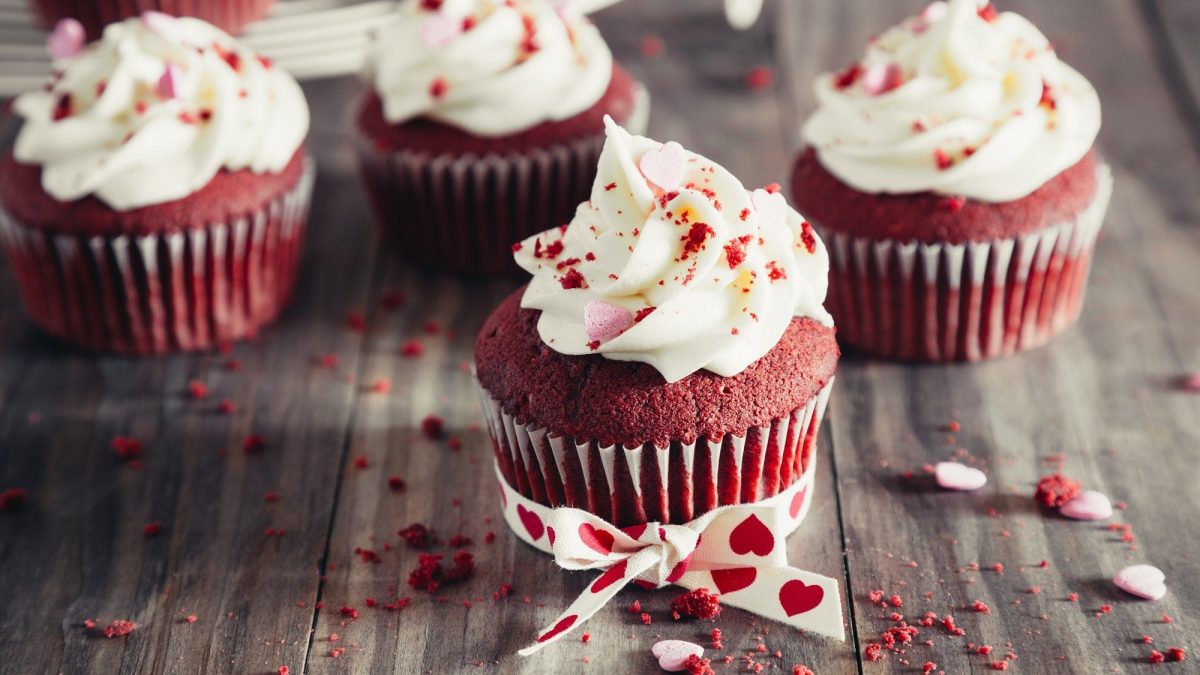 Red Velvet Cupcakes auf einem rustikalen Holztisch, dekoriert für den Valetinstag.