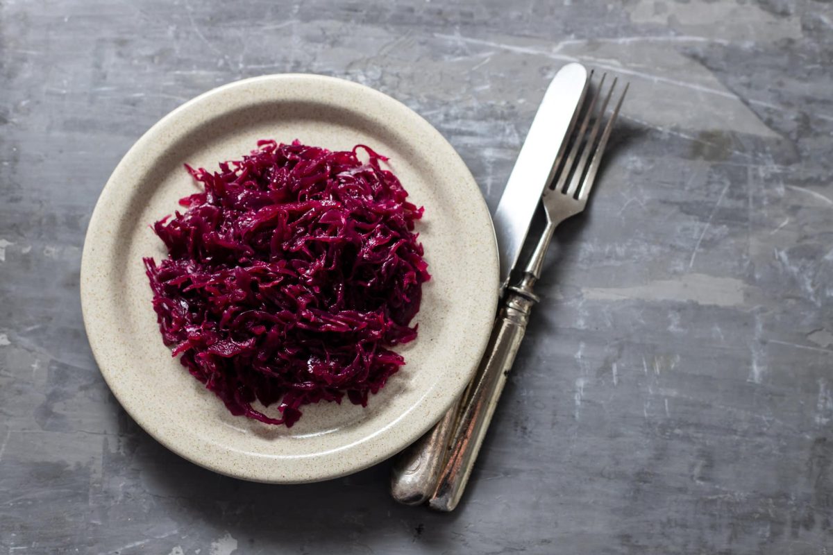 Weißer Teller mit Rotkohl auf grauem Untergrund