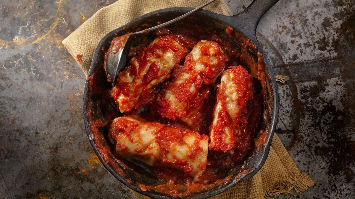 In einer rustikalen Messingpfanne angerichtete Kohlrouladen in einer Tomatensauce