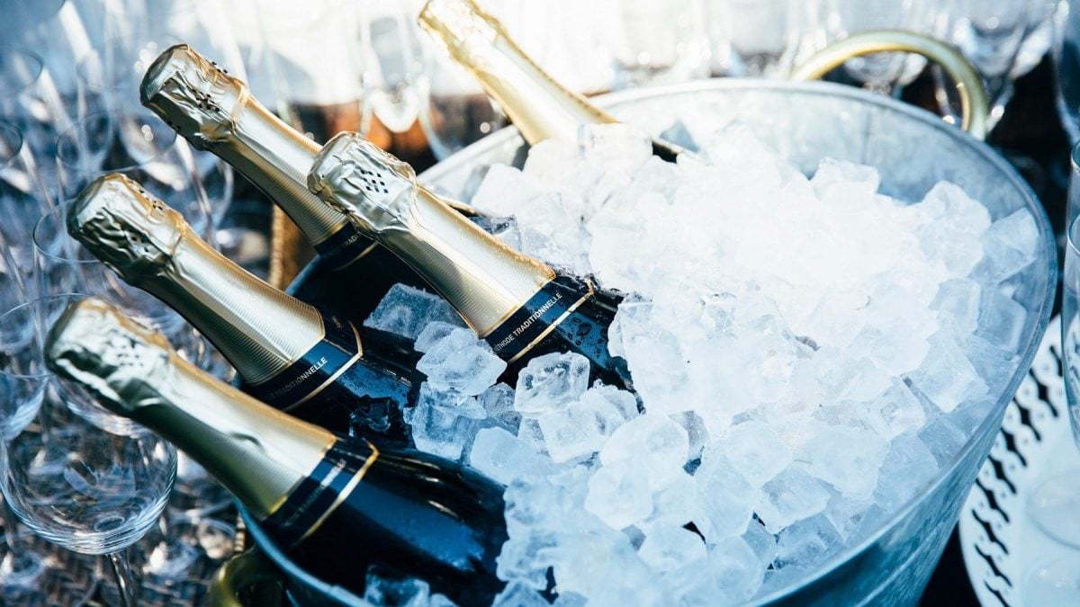 in einem Eiskübel liegen sechs Flaschen Champagner..