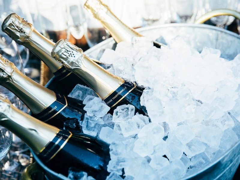 in einem Eiskübel liegen sechs Flaschen Champagner..