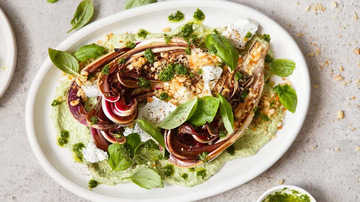 Ein Teller gebackener Radicchio mit Erbsen-Basilikum-Hummus und zerbröseltem Feta in der Draufsicht.