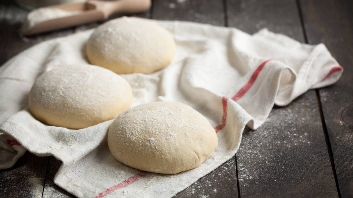 Germknödel mit Mehl ummantelt auf einem weißen Tuch auf hölzerner Arbeitsfläche