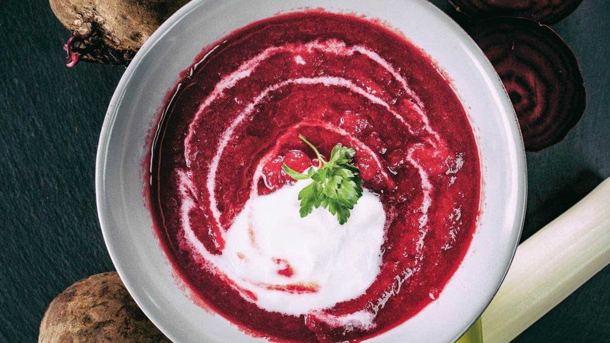 Cremige Rote Bete-Suppe mit Poree und einer Schmandhaube in einer weißen Schale serviert