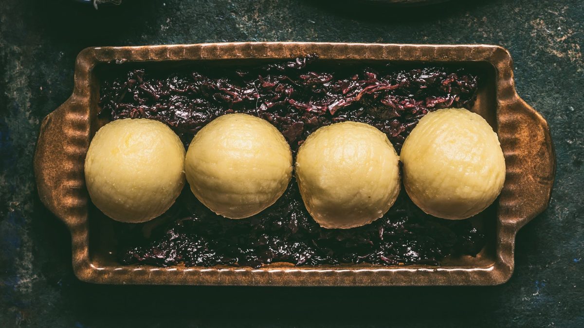 Traditionelle Kartoffelknödel in einer Form auf Rotkraut auf schwarzem Untergrund