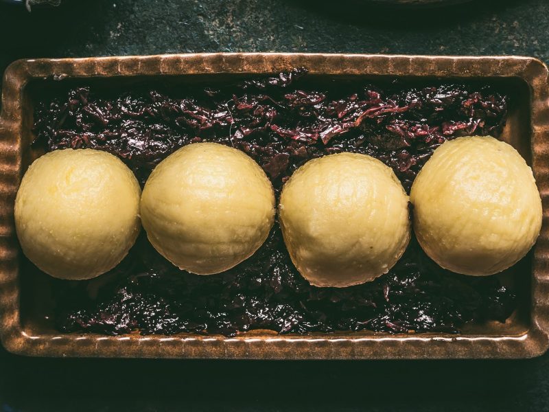 Traditionelle Kartoffelknödel in einer Form auf Rotkraut auf schwarzem Untergrund
