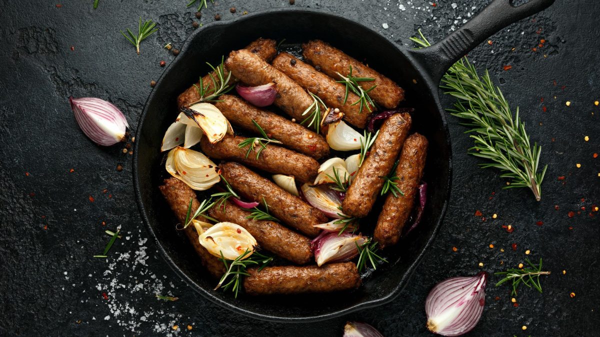 Eine Pfanne auf dunklem Schiefer in der Draufsicht, darin vegane Chorizo in Rotwein, Schalotten und Rosmarin.