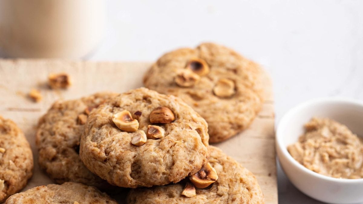 Auf einem Brett liegen vegane Haselnussplätzchen, daneben steht eine Schale mit gemahlenen Nüssen.