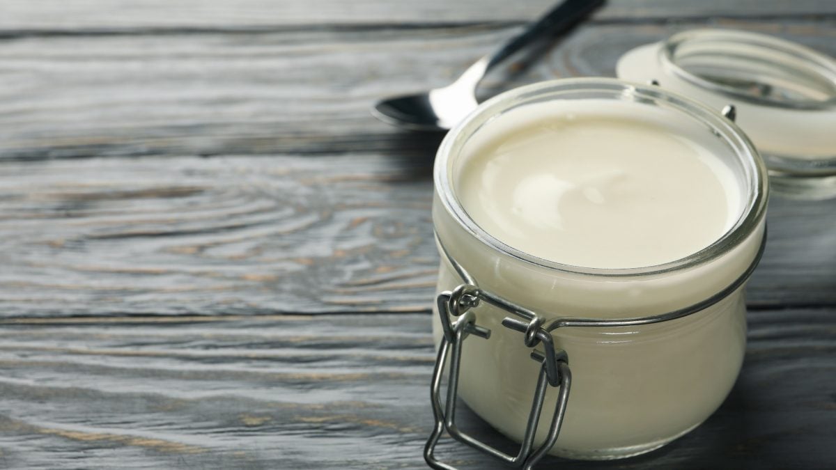 Selbstgemachte vegane Mayonnaise in einem kleinen Einmachglas auf hölzernem Untergrund
