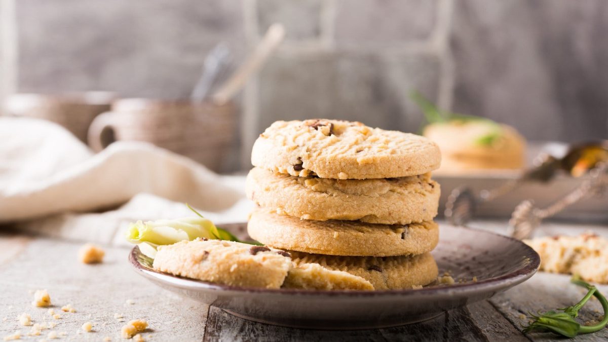 Ein Teller mit einem Stapel veganer Orangen-Schoko-Plätzchen, dahinter ist unscharf Küchenausstattung zu erkennen.