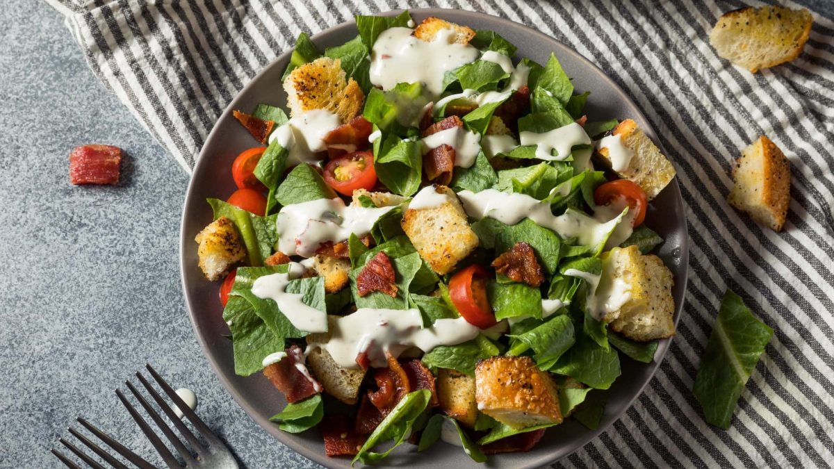 Ein prallgefüllter Teller mit Bacon, Salat, Tomaten, Brotwürfel und Dressing: unser BLT-Salat.