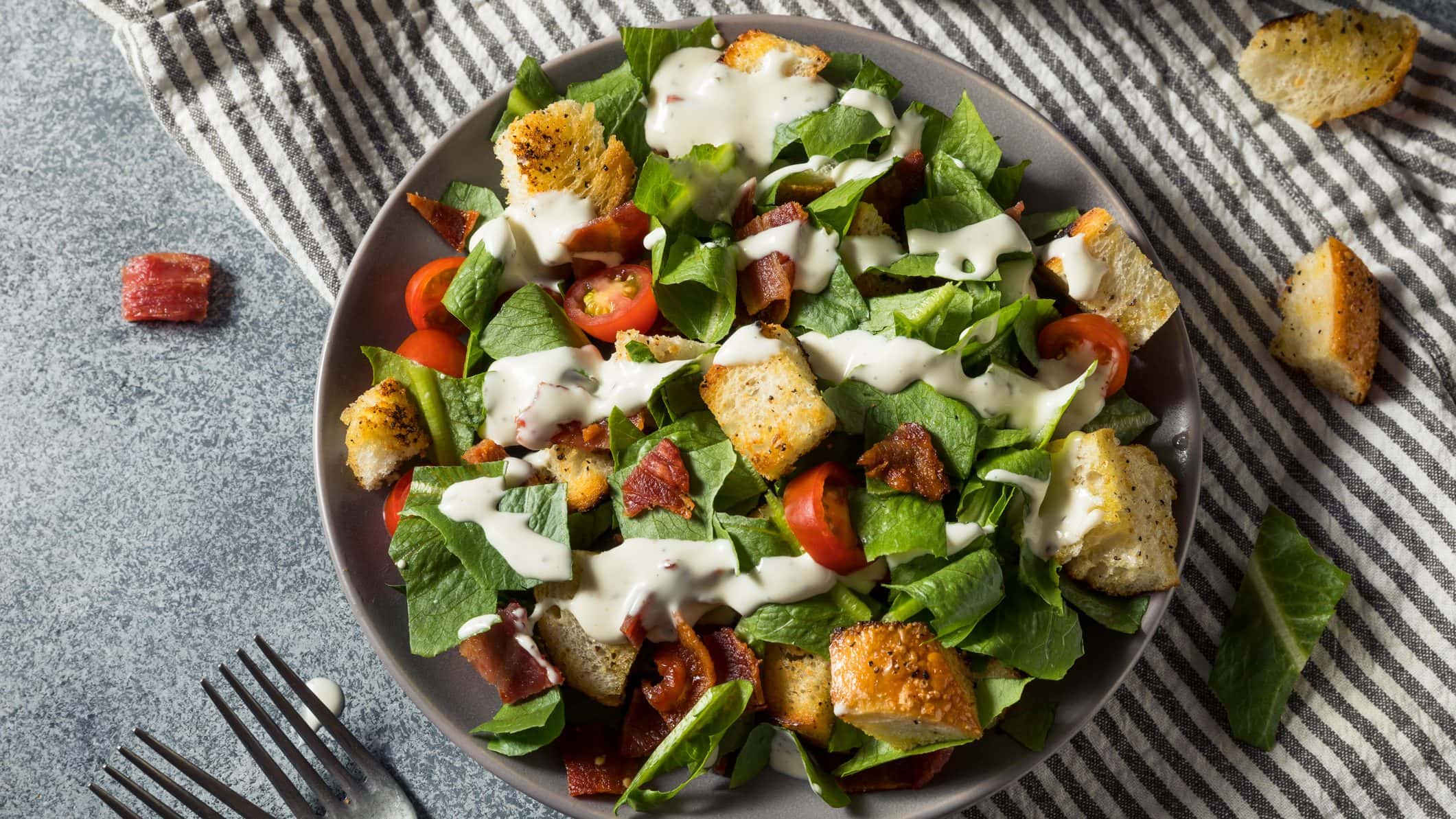 Ein prallgefüllter Teller mit Bacon, Salat, Tomaten, Brotwürfel und Dressing: unser BLT-Salat.