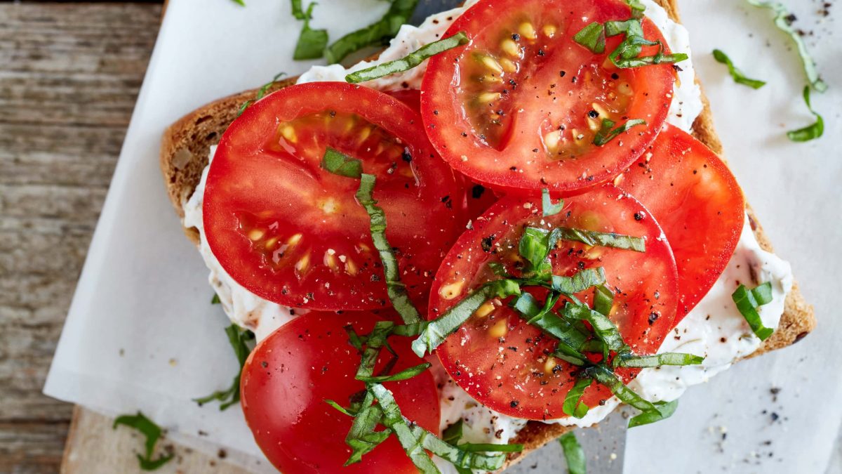 Tomaten-Sandwich mit Quark auf Brettchen serviert.