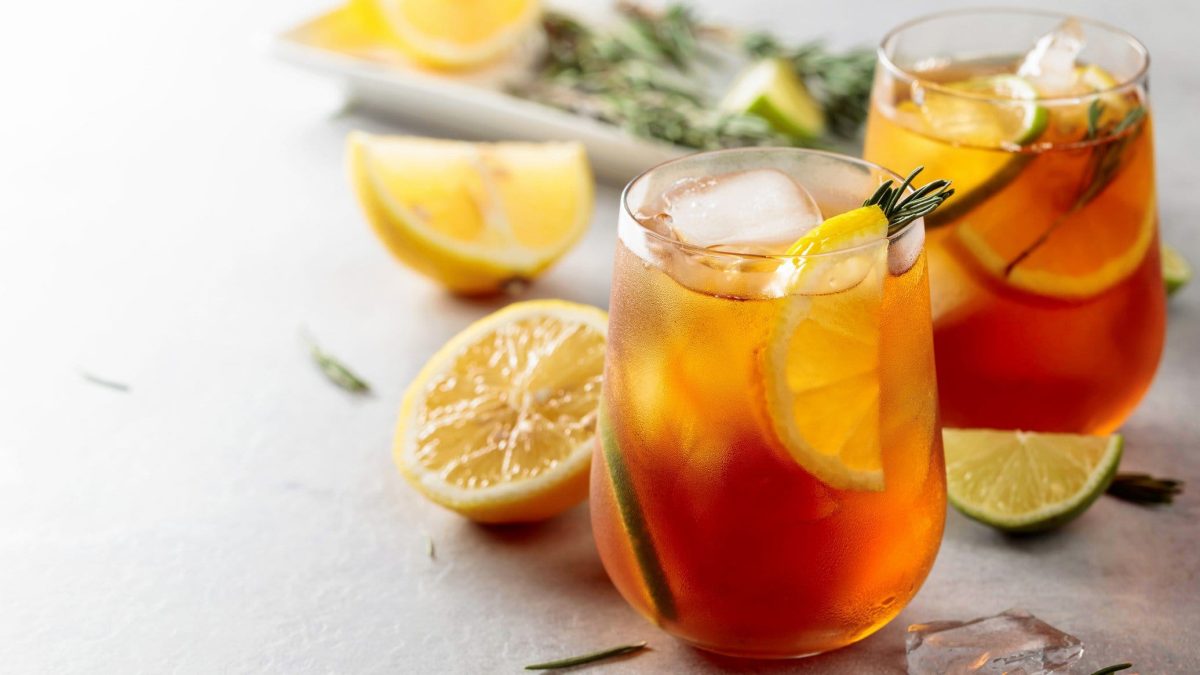 Zwei Gläser Earl Grey Gin Tonic mit Zitronenscheiben, Eis und Rosmarinzweigen. Im Hintergrund unscharf die Zutaten.