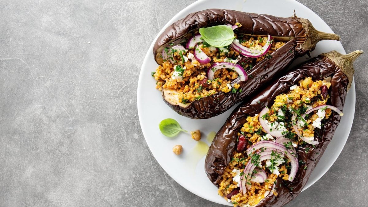 Ein Teller mit gebackener Aubergine mit Bulgur, roten Zwiebeln und Kichererbsen.