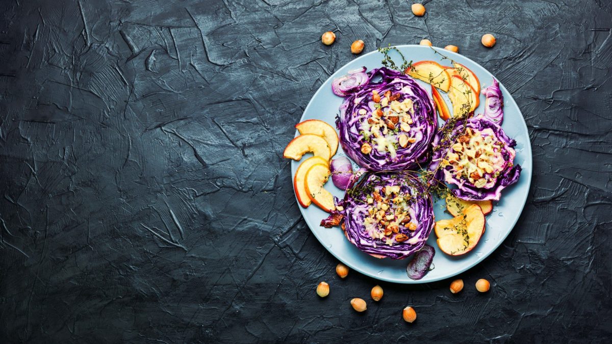 gebackener Rotkohl mit Sesamsauce und Äpfeln auf dunklem Untergrund in der Draufsicht.