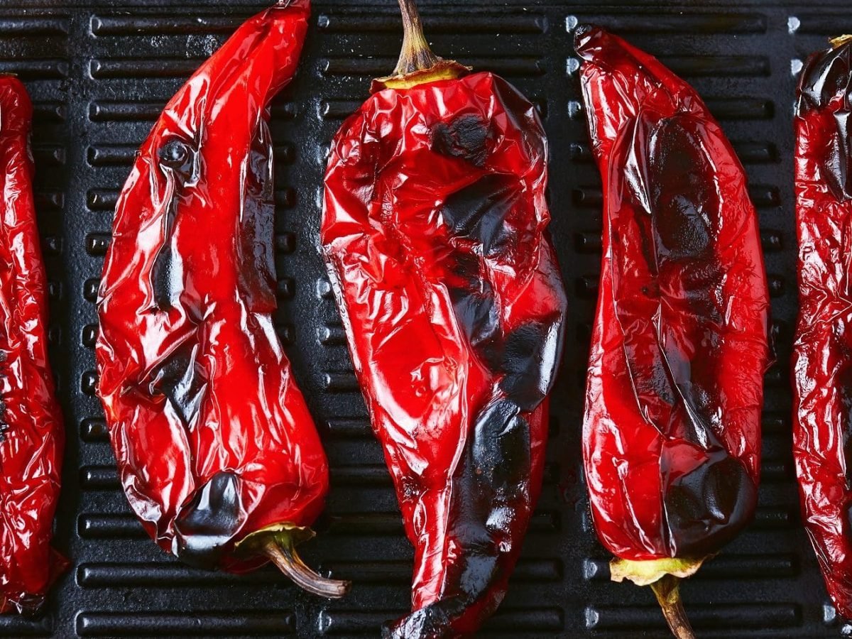 Aus der Vogelperspektive: In einer Grillpfanne liegen fünf gegrillte Paprikaschoten.