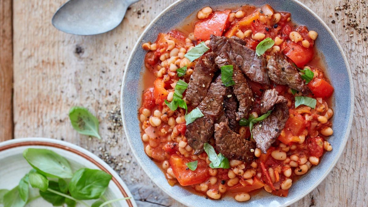 Zart gebratenes Hüftsteak in Streifen angerichtet auf einem Sud aus Baked Beans und Paprika.