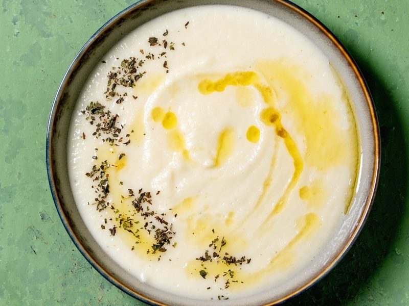 Eine Schale Pastinaken-Senf-Suppe mit getrockneten Kräutern und Öl.