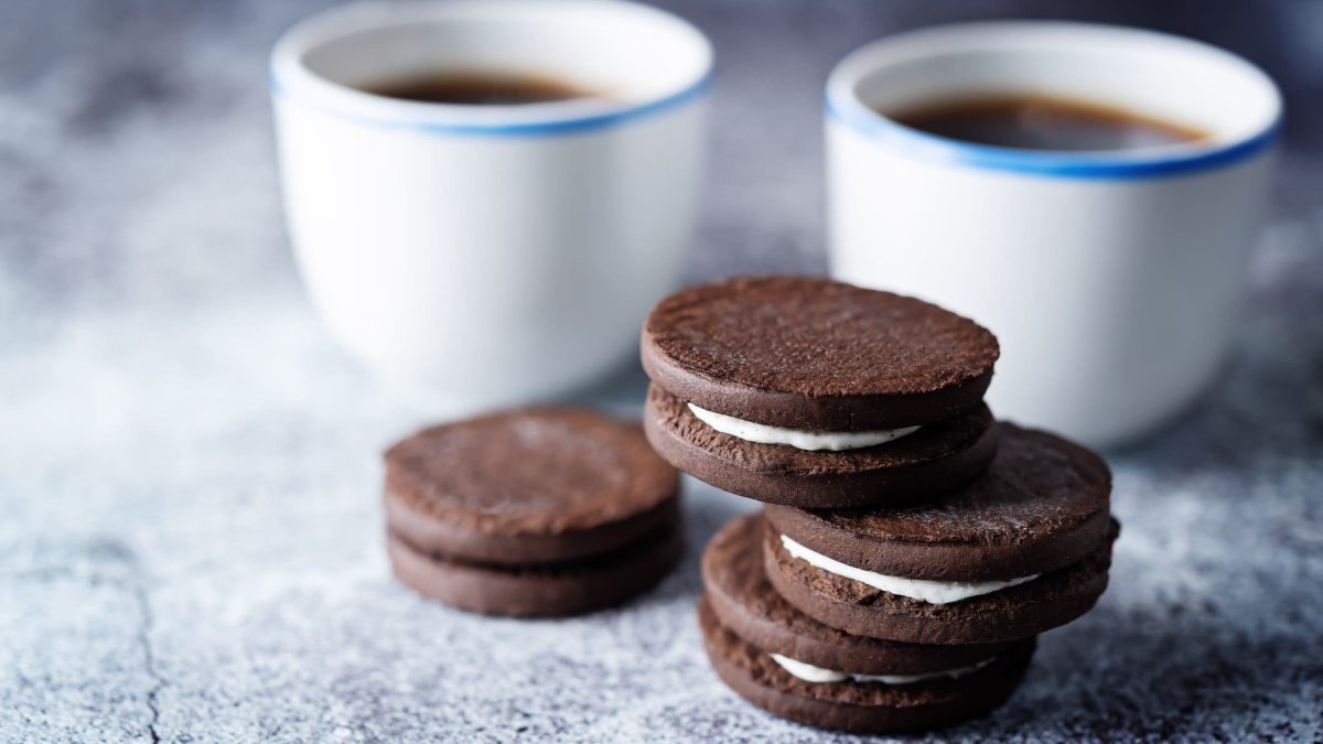 Ein Stapel selbst gemachte Oreos, dahinter unscharf zwei Kaffeebecher.