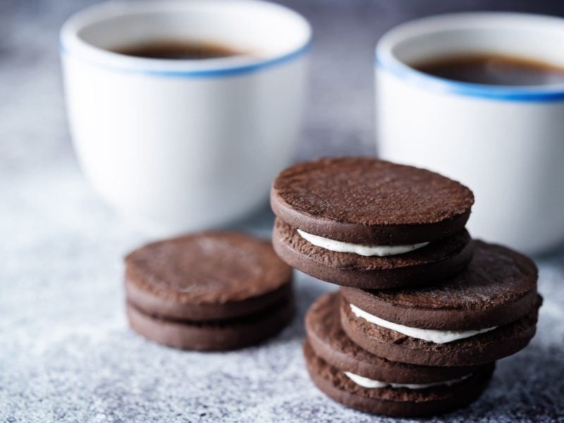 Ein Stapel selbst gemachte Oreos, dahinter unscharf zwei Kaffeebecher.
