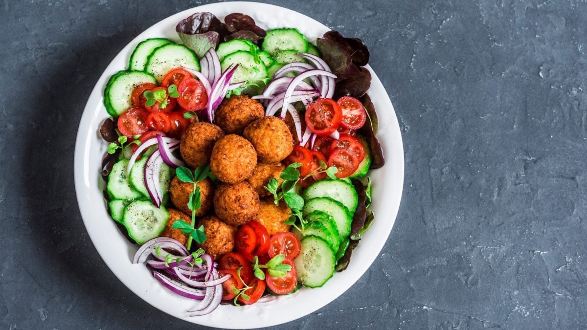 Süßkartoffel-Falafel mit Salat auf einem grauen Untergrund in der Draufsicht.