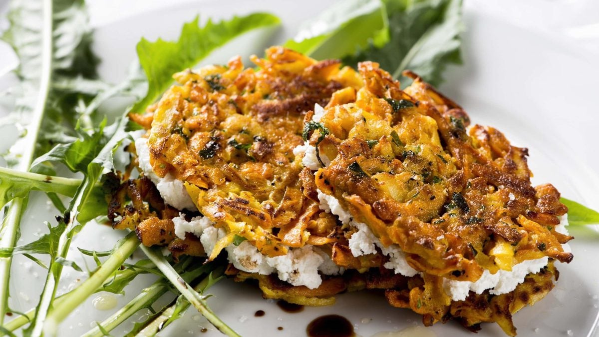 Knusprige Süßkartoffel-Fritters mit Kräutern und Ziegenkäsefüllung auf einem Salatbett aus Läwenzahn mit Balsamico und Öl