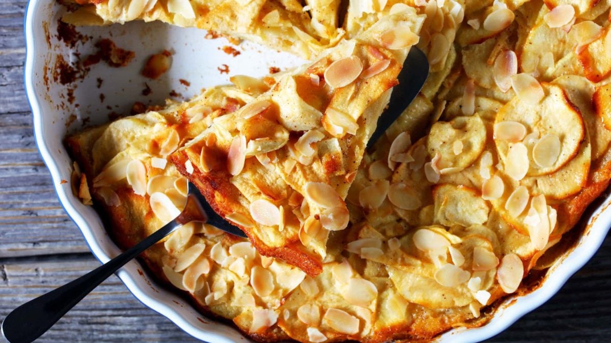 Unsichtbarer Apfelkuchen "Gâteau invisible aux pommes" in Tarteform auf hölzernem Untergrund.